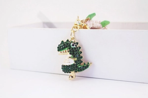 Close-up of green rhinestone dinosaur keychain with gold-tone metal clasp and ring