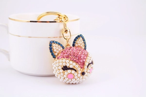 Gros plan du porte-clés renard en cristaux roses et bleus sur une tasse blanche