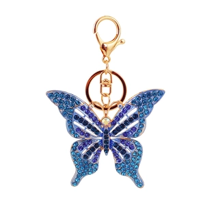 Porte-clés papillon doré avec cristaux bleus et violets sur fond blanc immaculé
