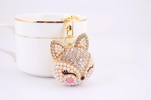 Détail du porte-clés renard avec perles et cristaux suspendu à une tasse de café blanche