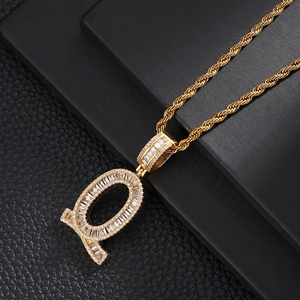 Macro shot of gold-plated letter Q pendant with baguette-cut zircons and twist chain