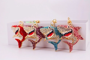 Détail de quatre porte-clés requin en strass de couleurs rouge, violet, bleu et rose