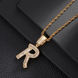 Detailed close-up of golden letter R pendant with sparkling baguette and round zircons
