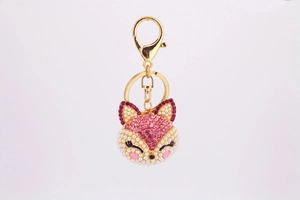 Détail d'un porte-clés renard avec perles, strass roses et fermoir mousqueton doré