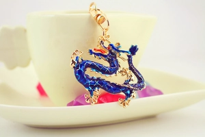 Close-up of blue enamel Chinese dragon keychain with gold edges on white ceramic background