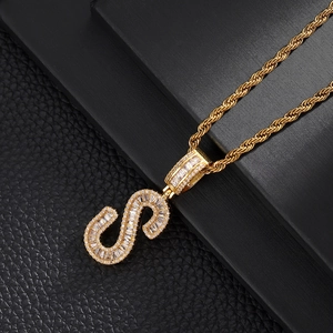 Close-up of golden letter S pendant necklace with cubic zirconia on black leather background