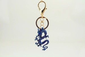 Detailed close-up of dark blue dragon keychain with golden lobster clasp and scale texture