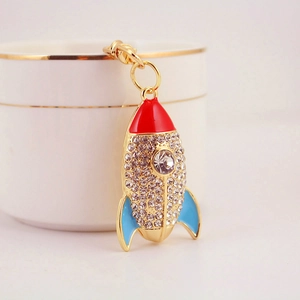 Porte-clés fusée doré serti de strass et émail coloré posé sur une tasse blanche