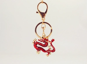 Close-up of golden dragon keychain with intricate red enamel detailing and lobster clasp