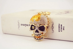 Détail d'un porte-clés tête de mort doré avec cristaux brillants et touches en émail punk