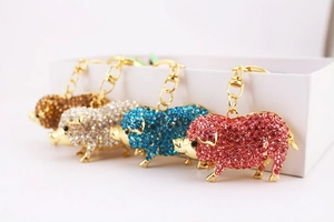 Détail de quatre porte-clés cochon en cristal rose, bleu, blanc et ambre avec fermoirs dorés