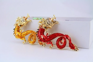 Close-up of red and orange enamel dragon pendants with sparkling crystals and gold details