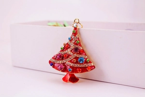 Macro detail of red enamel Christmas tree charm with colorful rhinestones on gold base