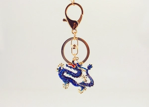 Close-up of blue enamel dragon keychain with gold metal edges and lobster clasp