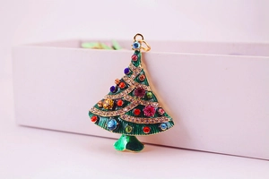 Macro shot of gold Christmas tree pendant with green enamel and multi-color rhinestones
