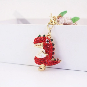 Sparkling dinosaur keychain featuring red rhinestones and golden metal hardware