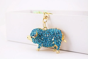 Gros plan d'un porte-clés cochon en cristal bleu avec fermoir mousqueton doré