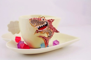 Détail d'un porte-clés requin avec strass roses et blancs sur une assiette cœur