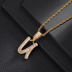 Macro shot of gold letter U pendant with baguette zircons on a black jewelry box