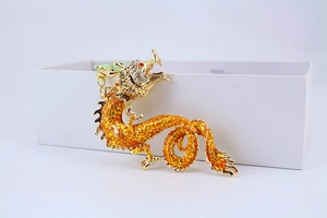 Macro detail of golden dragon keychain with red crystal eyes and white rhinestones