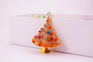 Close-up of golden Christmas tree pendant with vibrant pink and blue rhinestones