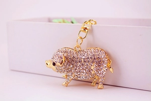 Détail du porte-clés cochon doré serti de cristaux blancs sur une boîte cadeau blanche