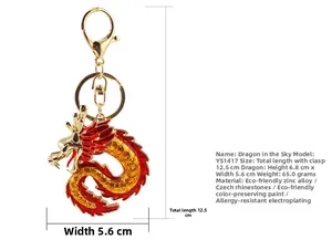 Detalle de un llavero de dragón dorado con esmalte rojo, cristales y hebilla en forma D