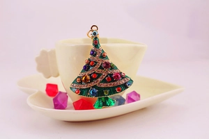 Detailed shot of Christmas tree keychain with colorful crystals on a warm gold surface