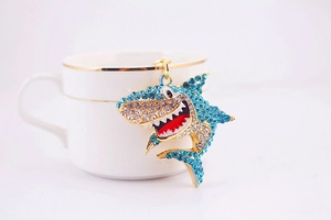 Détail d'un porte-clés requin en strass bleus accroché au bord d'une tasse blanche