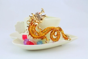 Detailed close-up of golden Chinese dragon keychain with orange enamel and white crystals