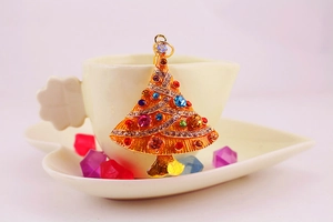 Close-up of a golden Christmas tree keychain pendant with colorful rhinestones on a cup edge