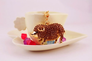 Détail du porte-clés cochon plaqué or orné de strass ambrés et d'un fermoir mousqueton