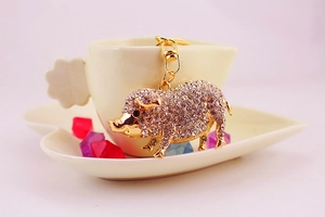 Détail du porte-clés cochon doré avec strass brillants et fermoir mousqueton robuste