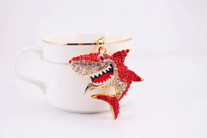 Détail du porte-clés requin avec strass rouges accroché à une tasse blanche