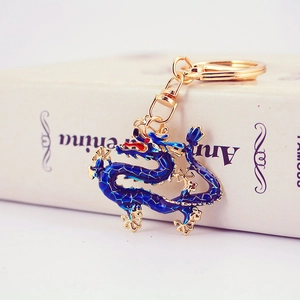 Traditional Chinese dragon keychain with dark blue enamel and gold-plated finish on a book