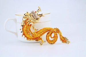 Macro shot of golden Chinese dragon pendant with orange enamel and sparkling white rhinestones