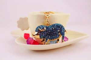 Détail d'un porte-clés cochon en cristal avec strass bleus sur une tasse en forme de cœur