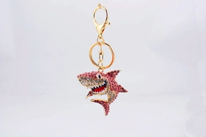 Détail d'un porte-clés requin en strass rose et blanc avec fermoir mousqueton doré