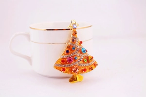 Detail view of a gold Christmas tree keychain with colorful rhinestones on a ceramic cup
