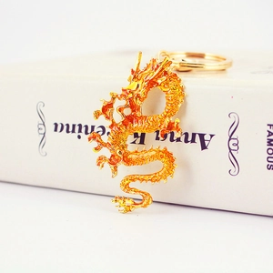 Golden dragon keychain with enamel finish on vintage book background, elegant car key accessory
