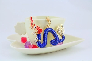 Dettaglio portachiavi drago con smalto blu e strass sul bordo di una tazza