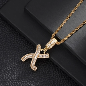 Macro detail of gold hip hop letter X pendant with square cubic zirconia and rope chain