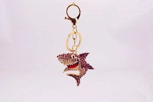 Détail d'un porte-clés requin avec des strass violets et un fermoir en métal doré brillant