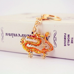 Golden Chinese zodiac dragon keychain with orange gradient enamel on a white book base