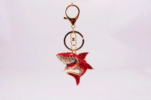 Détail d'un porte-clés requin doré orné de strass brillants rouges et blancs