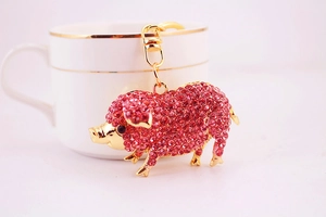 Détail du porte-clés cochon en cristal rose plaqué or suspendu à une tasse à café