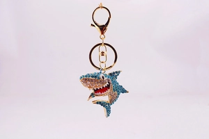 Détail du porte-clés requin avec strass bleus, alliage doré et bouche en émail rouge
