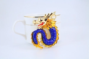 Detalle macro de llavero de dragón de esmalte azul colgado en una taza blanca
