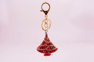 Close-up of golden Christmas tree keychain with red enamel and colorful rhinestones