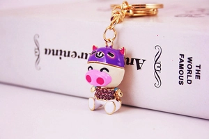 Dettaglio macro di un simpatico portachiavi a forma di maiale con strass e casco viola